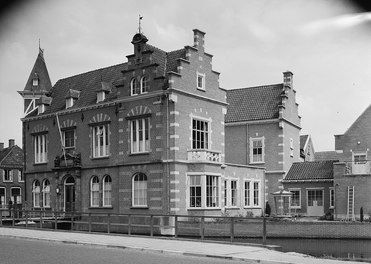 Het voormalige gemeentehuis van Borculo tijdens de naoorlogse uitbreidingsjaren waarin ook de woonbuurten rond de Lochemseweg verrezen (juli 1956)