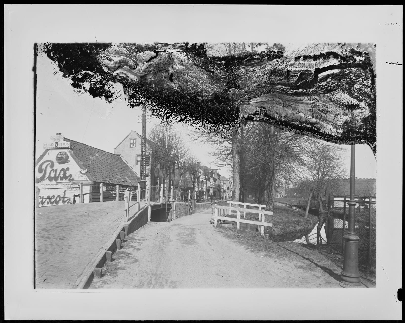 De Smidsbrug waar het Zuidereinde overgaat in het Noordereinde, met zicht op het Noordereinde. Het lage deel van de brug was voor de paardentram. Glasnegatief met beschadigde emulsie, 1925-1930.